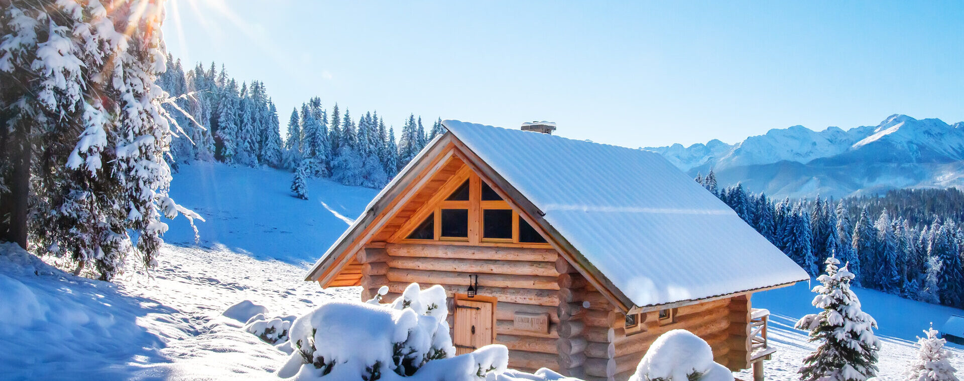 Winterberglandschaft in den Alpen, mit schneebedeckter Skihütte an einem sonnigen klaren Tag