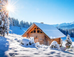 Winterberglandschaft in den Alpen, mit schneebedeckter Skihütte an einem sonnigen klaren Tag