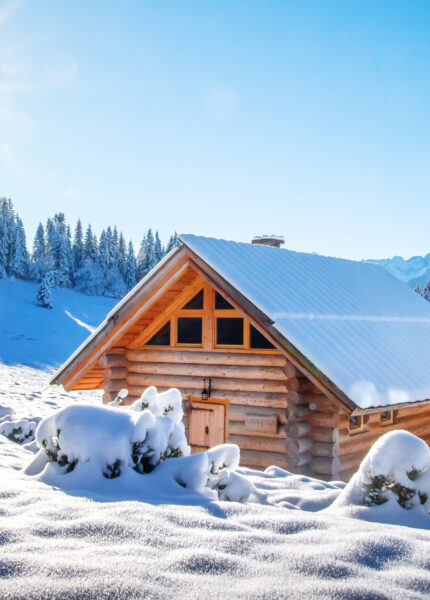Winterberglandschaft in den Alpen, mit schneebedeckter Skihütte an einem sonnigen klaren Tag