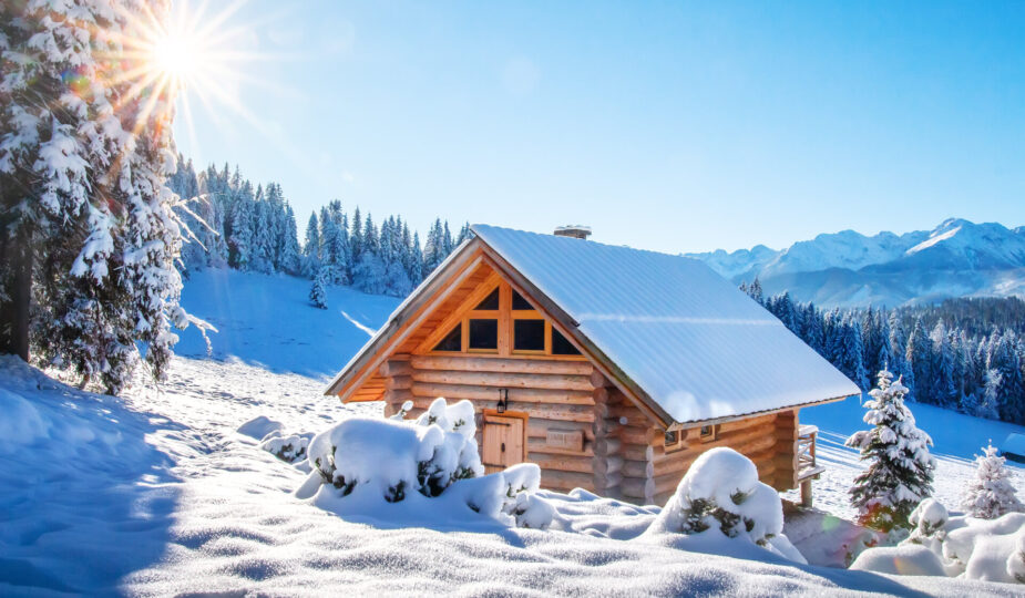 Winterberglandschaft in den Alpen, mit schneebedeckter Skihütte an einem sonnigen klaren Tag