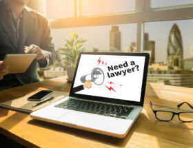 Männliche Person mit Blick auf einen Tablet-Bildschirm, auf dem die Frage "Brauchen Sie einen Anwalt?" steht