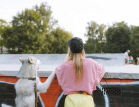 Frau und Hund an einem Betonzaun