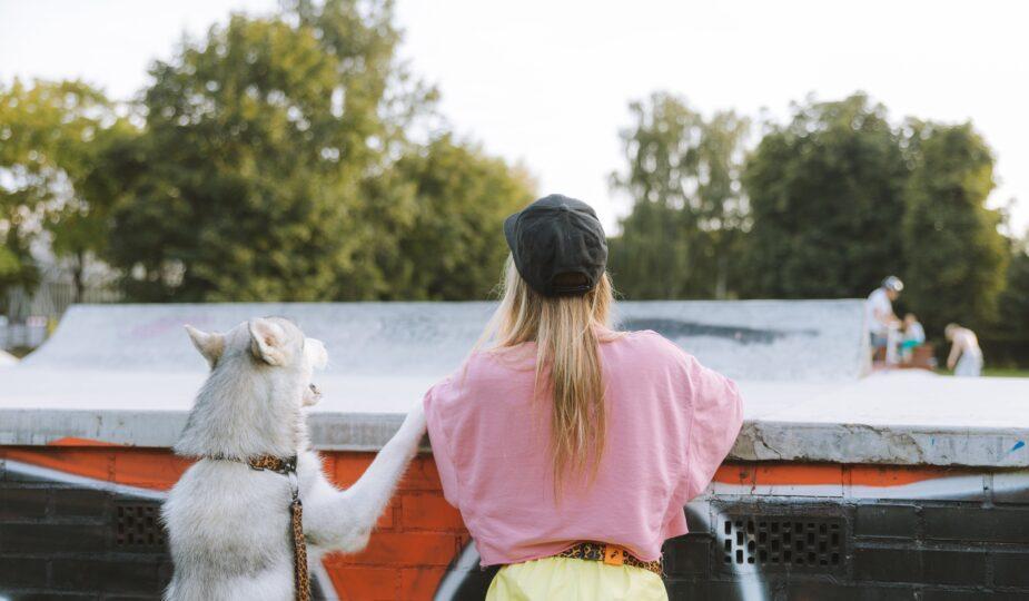 Frau und Hund an einem Betonzaun