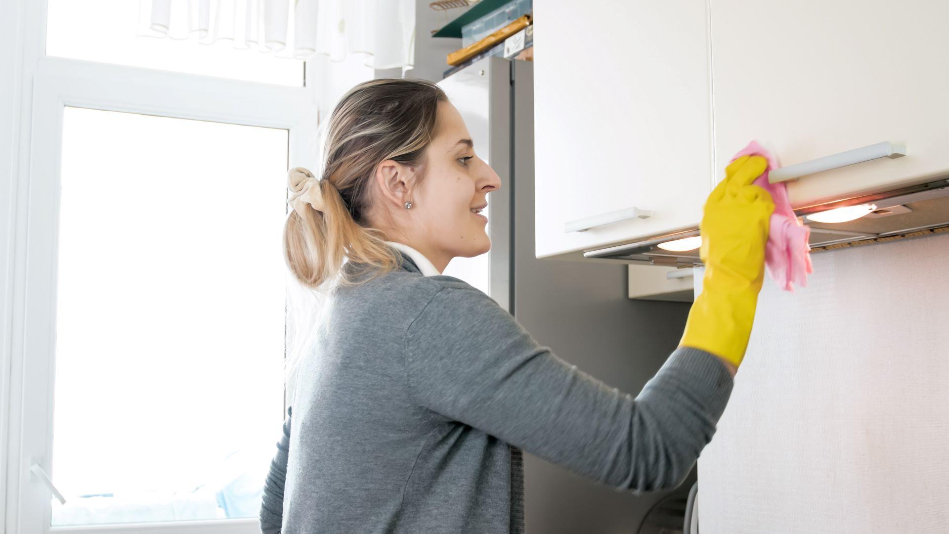 Haushälterin reinigt Küche mit gelben Handschuhen